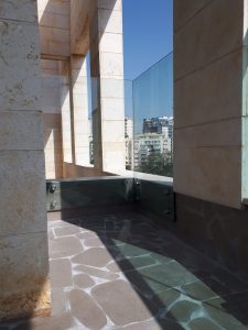 מרפסת, מעקה זכוכית, עמודי אבן, נוף עירוני