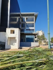 אתר בנייה, בניין מודרני, חזית זכוכית, גזעי דקל